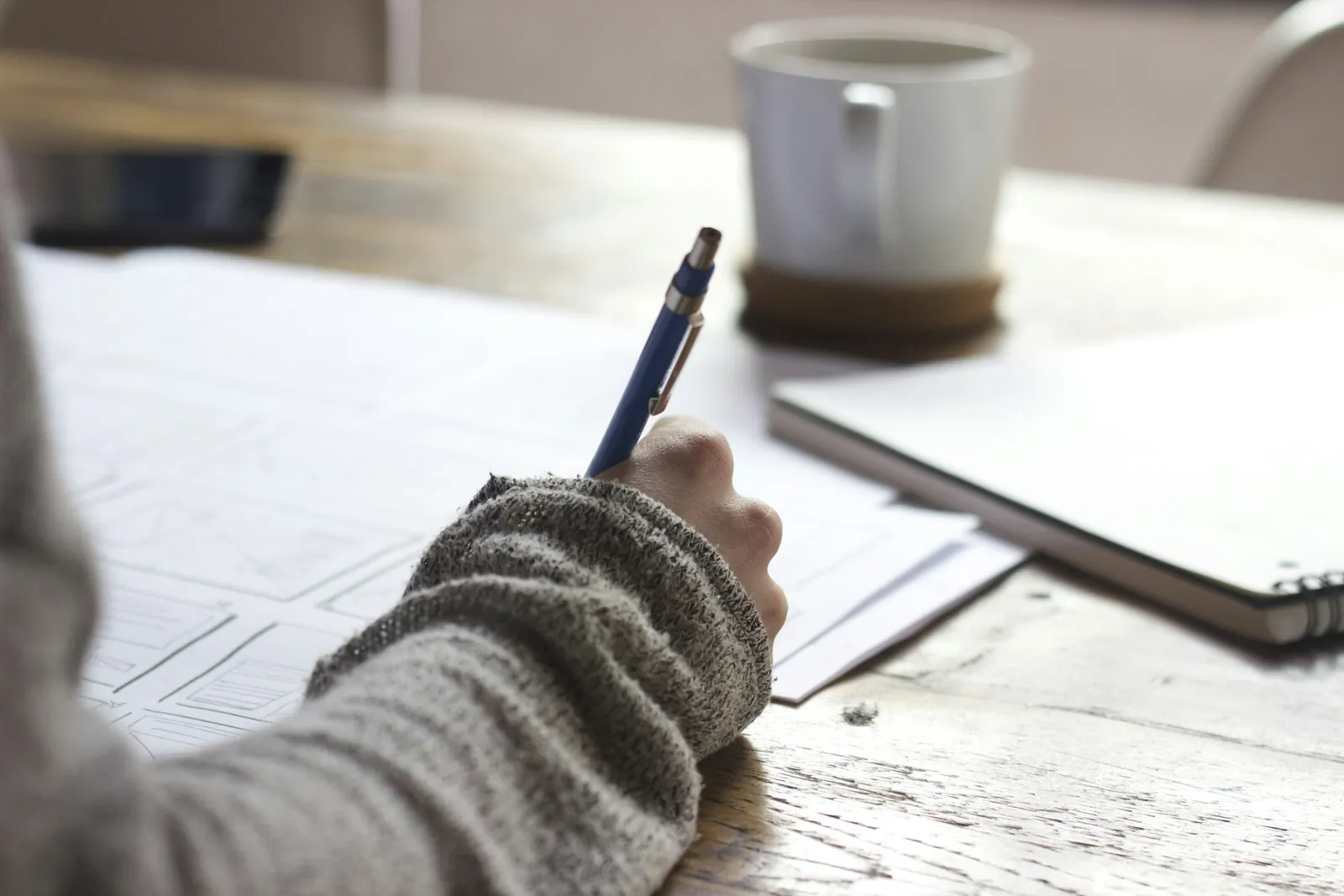 An author making notes on a manuscript beside a cup of coffee